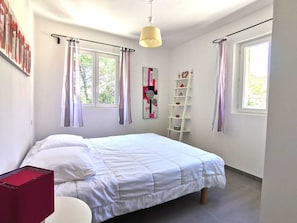 A bedroom with a bed, a red cabinet, a white chair, a ladder shelf, and a window with curtains. - Recent villa 3 bedrooms, quiet village charm, pool near Aix and Luberon (Rognes)