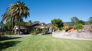 A residential property with a well-maintained lawn, a swimming pool, and a house with a sloped roof.