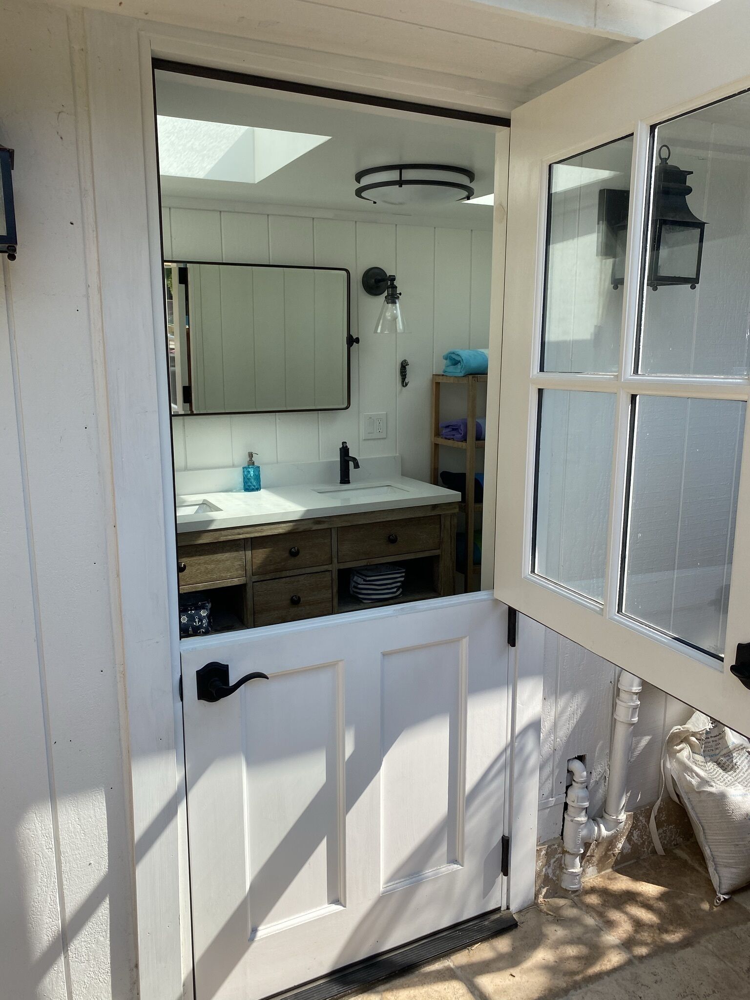 A bathroom with a white vanity, a mirror, a towel rack, and a window.