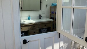 A bathroom with a white vanity, a mirror, a towel rack, and a window.