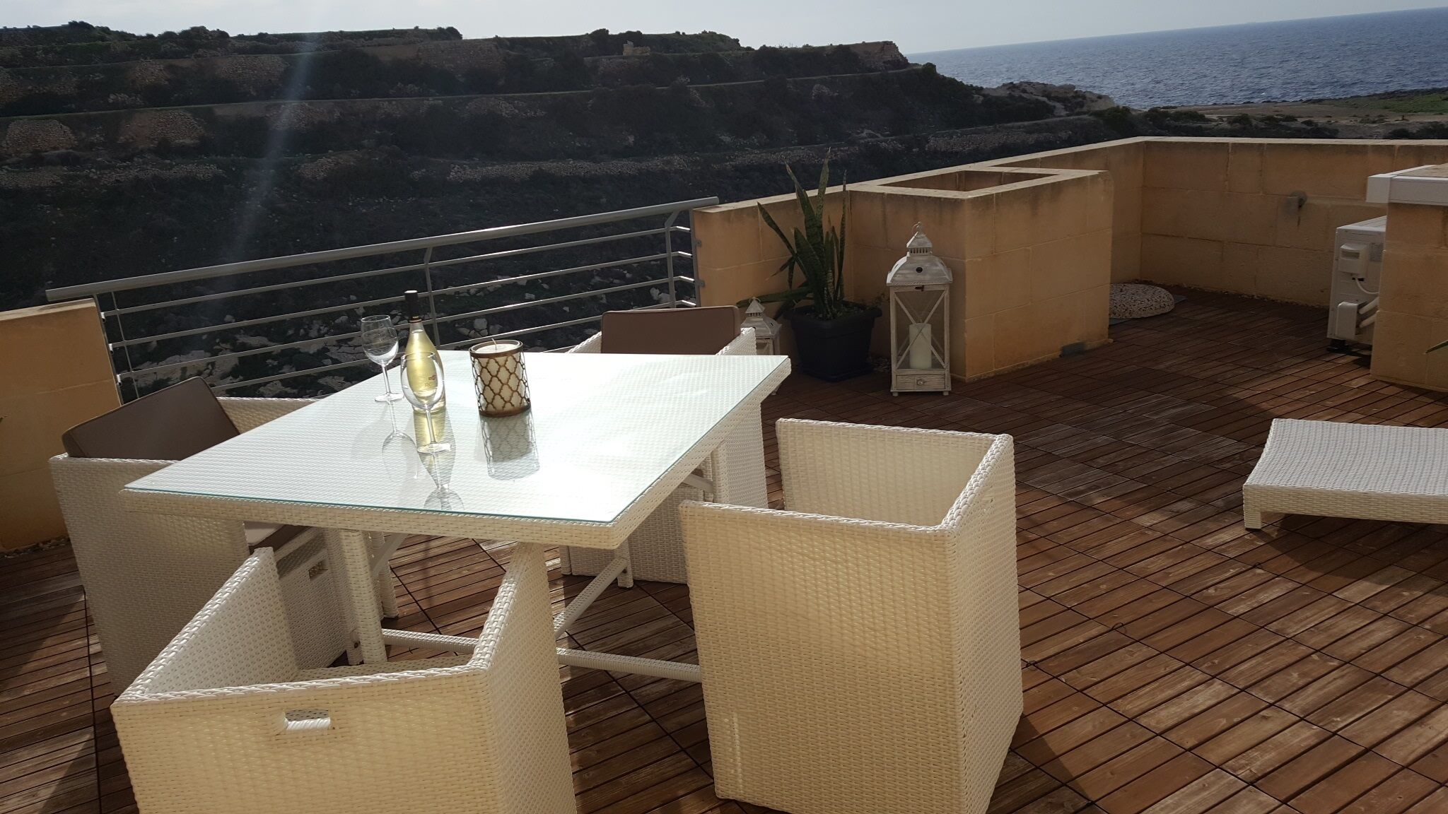Une terrasse avec une table et des chaises, un pot de fleurs et une vue sur la mer.