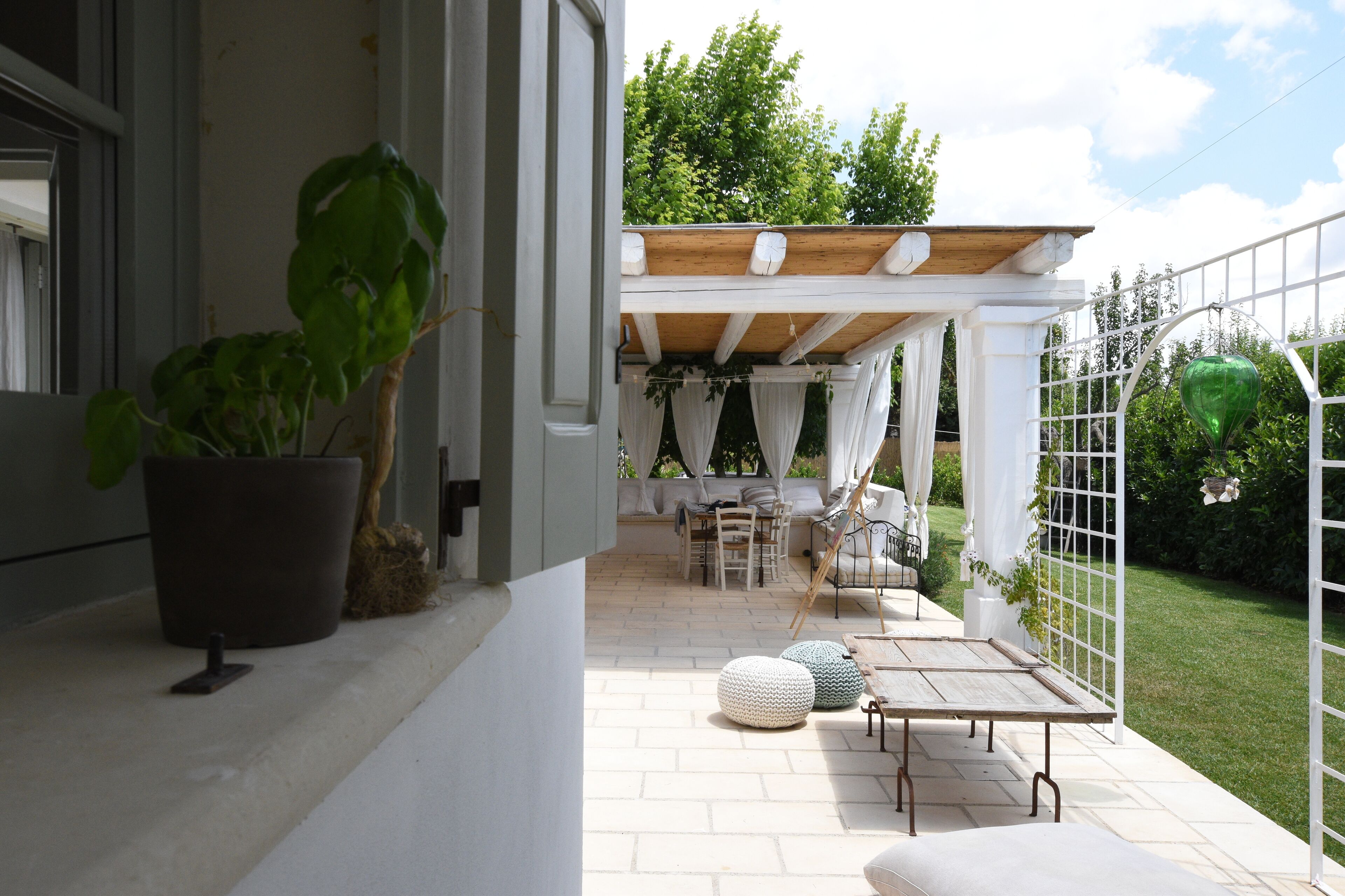 Eine Terrasse im Freien mit einer Holz-Pergola, einer Sitzgelegenheit und Kübelpflanzen.