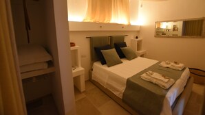 Une chambre d’hôtel avec un lit, des tables de chevet, un miroir et une fenêtre avec des rideaux.