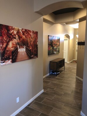 Stunning artwork adorns the walls of this elegant hallway, featuring a large bridge and a colorful tree.