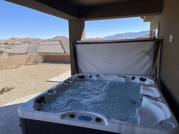 Relax in a hot tub under a covered area with a scenic mountain view.