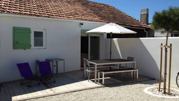 Eine Terrasse mit Tisch und Stühlen, ein überdachter Bereich und ein kleiner Tisch mit einem violetten Stuhl.