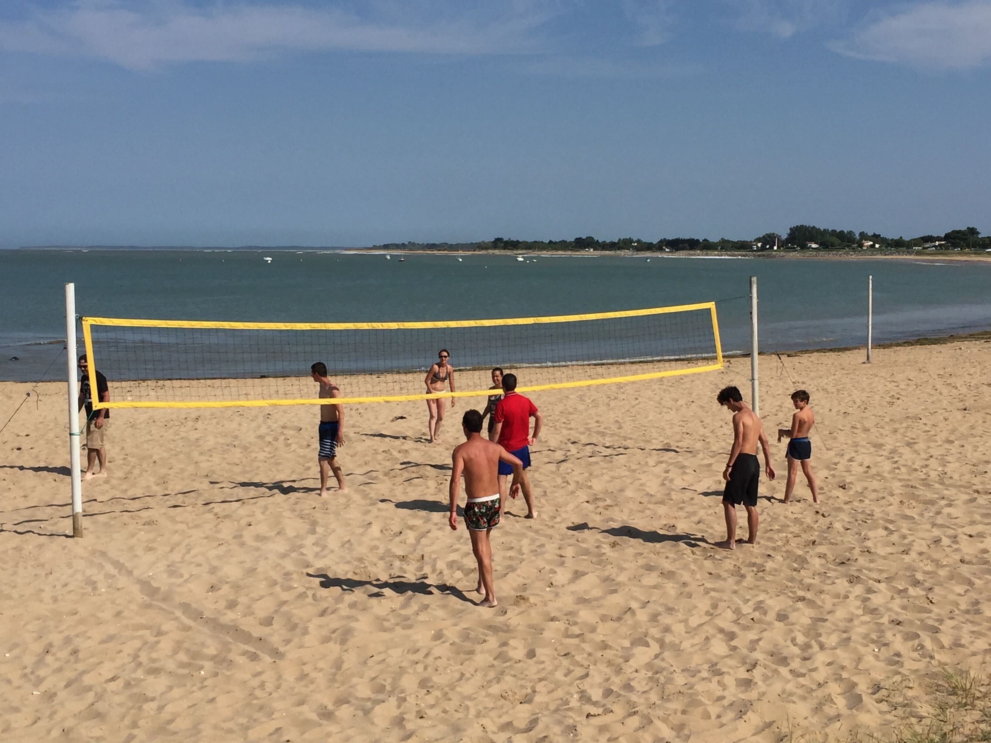 A beach volleyball game on a sandy beach with a clear sky.