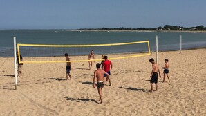 Una partita di beach volley su una spiaggia sabbiosa con cielo sereno.