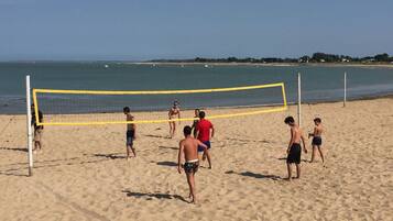 A beach volleyball game on a sandy beach with a clear sky.