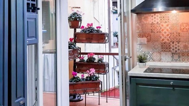 Una cocina con lámpara colgante, salpicadero de azulejos y techo de madera.