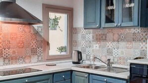 Una cocina con armarios azules, un salpicadero con diseño, un tapete rojo y una ventana con vistas.