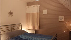 A bedroom with a bed, a window with a curtain, a wall-mounted star decoration, and a framed picture.