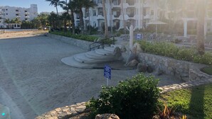 Een hotel aan het strand met een zwembad, palmbomen en een heldere lucht.