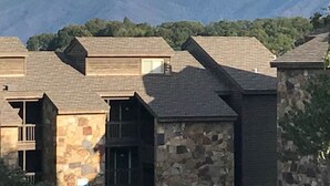A row of rustic cabins with stone walls and pitched roofs, set against a backdrop of mountains.