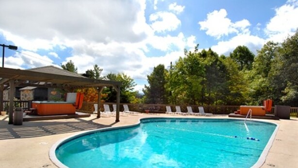 A swimming pool with lounge chairs and a covered area with a barbecue.