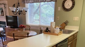 A kitchen with a central island, wooden cabinets, a dishwasher, a sink, and a window with blinds.