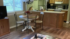 A modern living room with a dining area, a kitchen, and a large window.