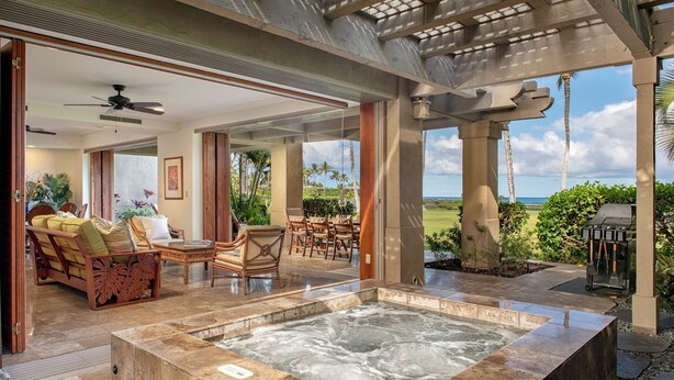 Amplio espacio interior con un jacuzzi, muebles de madera y vista al océano.