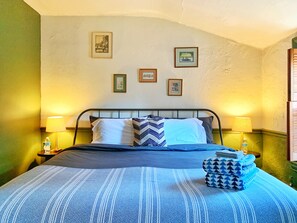 A neatly made bed with a striped blue and white bedspread, two pillows, and a blue and white patterned throw. There are two bedside lamps, a framed picture on the wall, and a small stack of folded towels on the bed. - The Historic & Walkable Philadelphia Washington Square West 2 bed/2 bath Home (Philadelphia)