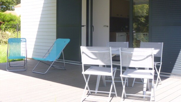 An outdoor patio with a table and chairs, a blue folding chair, and a sliding glass door leading to a kitchen area. - Villa 500 m from Ste Marguerite beach (Pornichet)