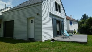A single-story house with a garage, a front door, and a small deck with a chair. - Villa 500 m from Ste Marguerite beach (Pornichet)