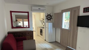 Un espace de vie compact comprenant un coin repas, une kitchenette et un grand miroir.
