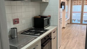 Une cuisine de taille réduite, équipée d’une cuisinière, d’un four à micro-ondes et de placards.