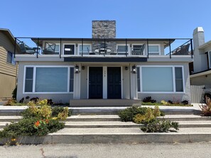 A modern two-story house with a balcony, large windows, and a stone chimney. - Beach House Overlooking Seacliff State Park and Rio Del Mar Beach, Aptos (Aptos)