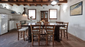 Una cocina rústica con vigas de madera, una mesa de comedor con sillas y un refrigerador blanco.