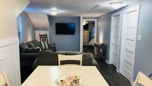 A compact living space with a dining table, a sofa, a TV, and a ceiling fan. - A Stone Throw Away from the Beach (Wildwood)