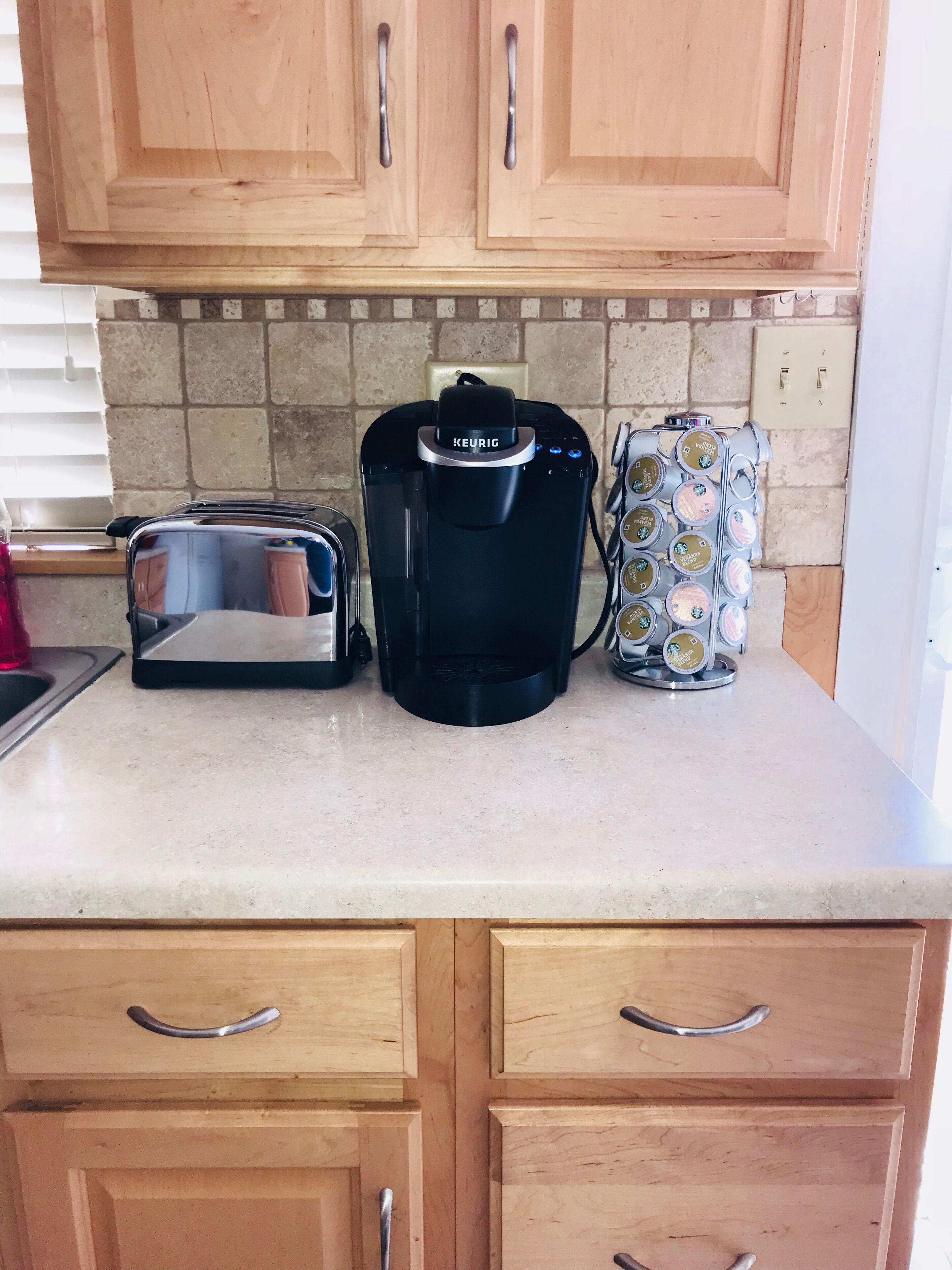 Eine Küche mit Holzausstattung, einem Toaster, einer Keurig-Kaffeemaschine und einer Kaffeemaschine für Kapseln.