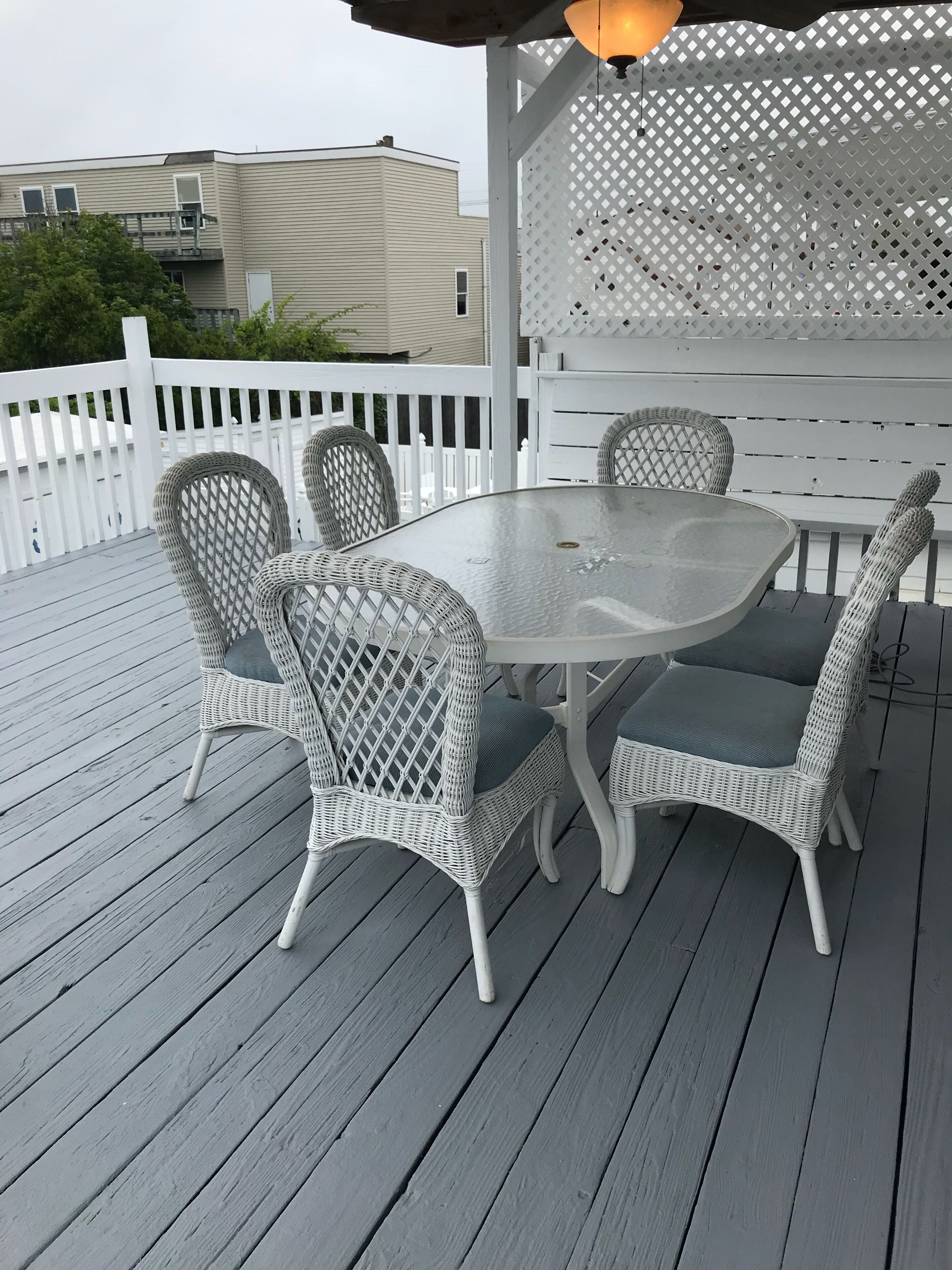 A covered outdoor patio with a round table and four wicker chairs.