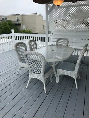 A covered outdoor patio with a round table and four wicker chairs.