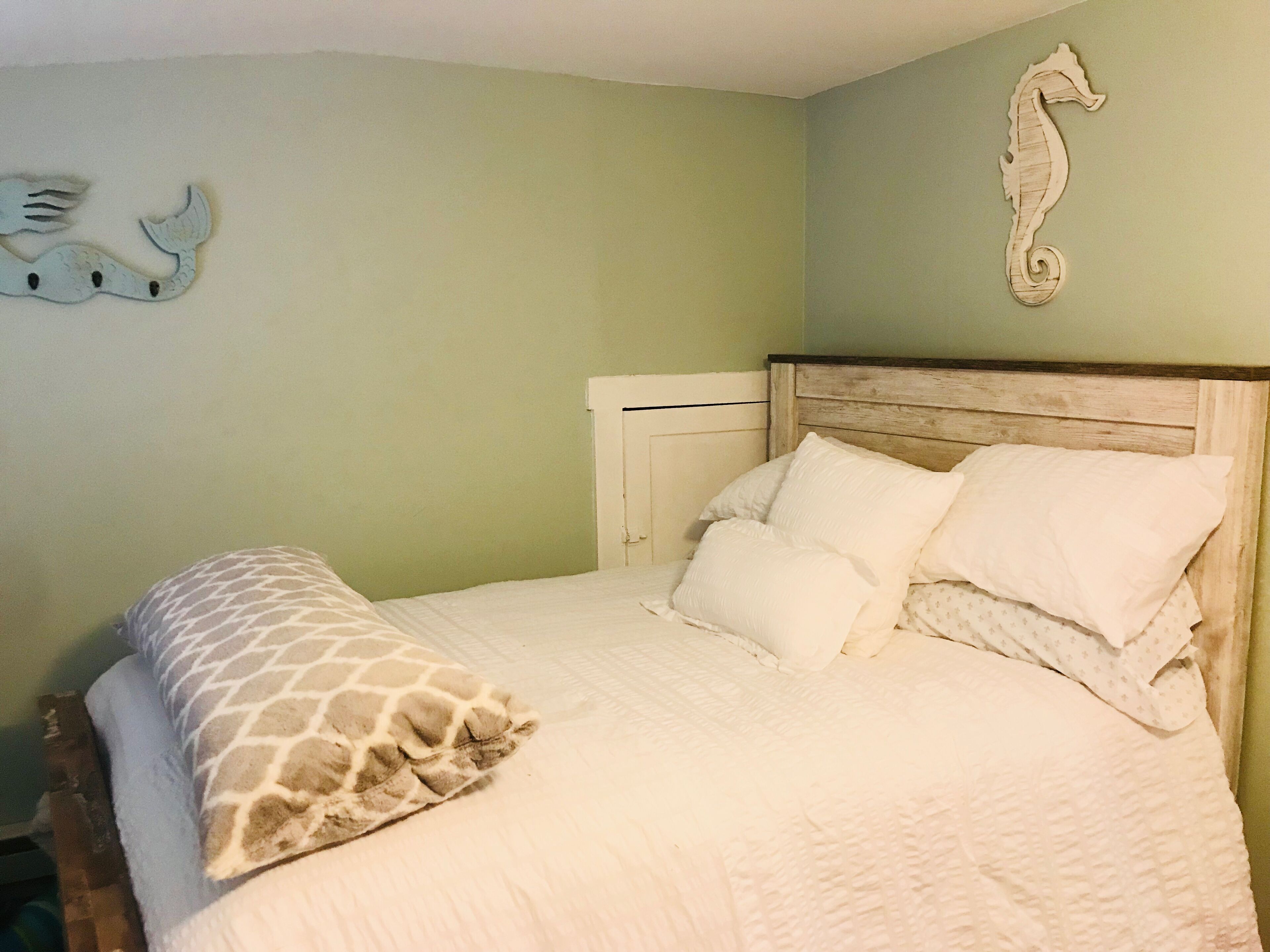 Un dormitorio con una cama, almohadas y una almohada estampada con diseño de jirafa.