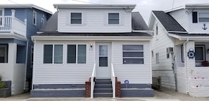 Enter a charming two-story home with a front entrance and stairs leading up to the door.