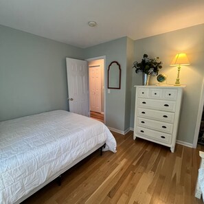 Une chambre à coucher avec un lit, une commode et une lampe.