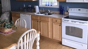 A kitchen with wooden cabinets, a white stove, a microwave, and a window with a view of the outdoors.