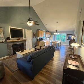 A living room with a fireplace, a sofa, and a dining area with a table and chairs. - Lakeside Haven, Cottage#4, Pool, Hot Tub, Lake View (Taylorsville)
