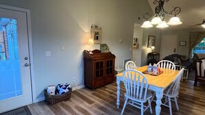 A dining area with a wooden table and white chairs, a dark wooden cabinet, and a chandelier. - Lakeside Haven, Cottage#4, Pool, Hot Tub, Lake View (Taylorsville)
