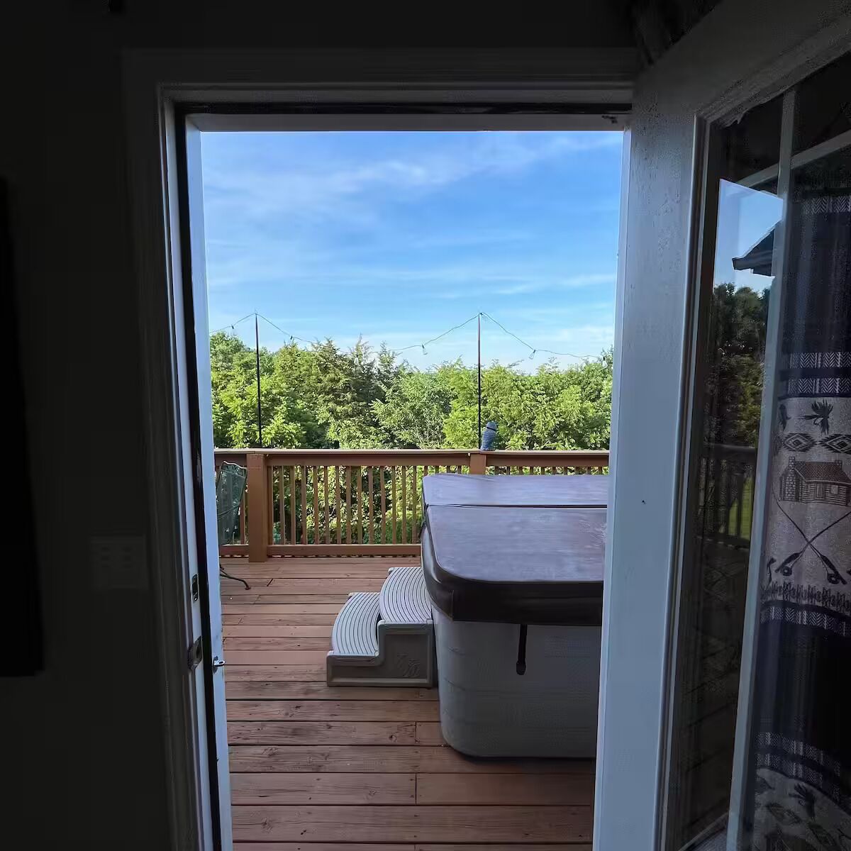 Une terrasse en bois dotée d’un espace salon abrité et offrant une vue sur la verdure.