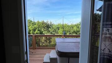 Une terrasse en bois dotée d’un espace salon abrité et offrant une vue sur la verdure.