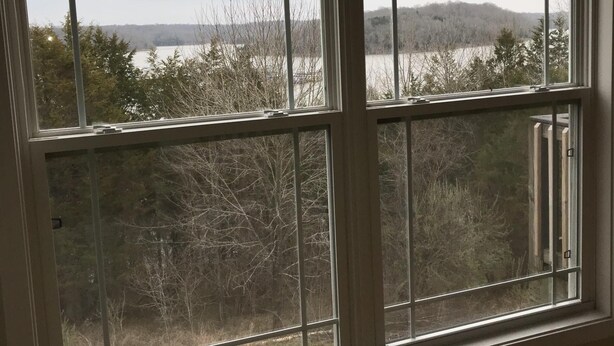 A room with a large window overlooking a lake and trees.