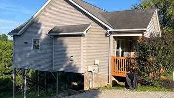 A two-story house with a front porch and a covered outdoor grill area.