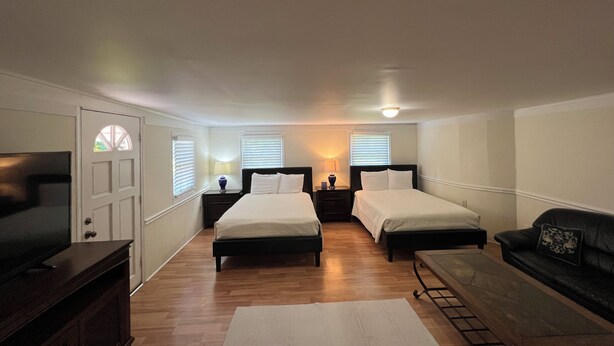 A bedroom with two beds, a TV, a sofa, and a desk. - A cozy single family home located right in the center of Augusta!  (Augusta)