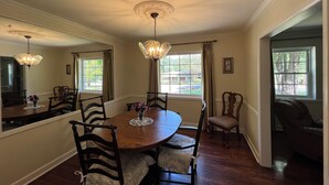 A dining room with a round table, chairs, a chandelier, and a view of the outdoors through windows. - A cozy single family home located right in the center of Augusta!  (Augusta)
