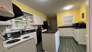 A kitchen with white cabinets, a black stove, and a green tiled floor. - A cozy single family home located right in the center of Augusta!  (Augusta)
