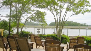 Une terrasse avec des chaises et des tables en bois donnant sur un plan d’eau.