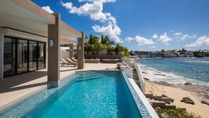 Un hôtel moderne doté d’une piscine offrant une vue sur une plage et l’océan.
