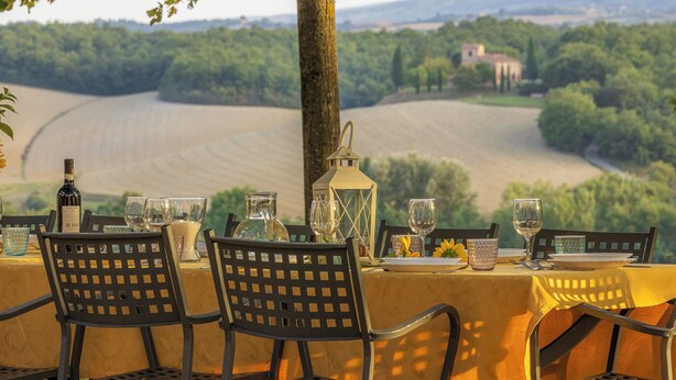 Une table dressée pour le dîner, avec vue sur un vignoble et des bâtiments situés au loin.
