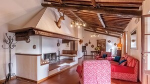 Un intérieur rustique avec un plafond en bois, une cheminée, un canapé rouge et un lustre.